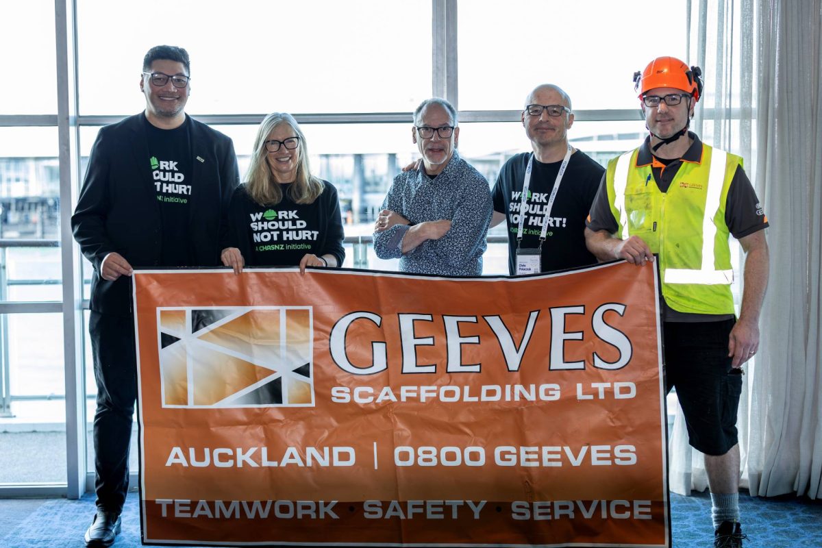 Group of people holding a Geeves Scaffolding banner indoors