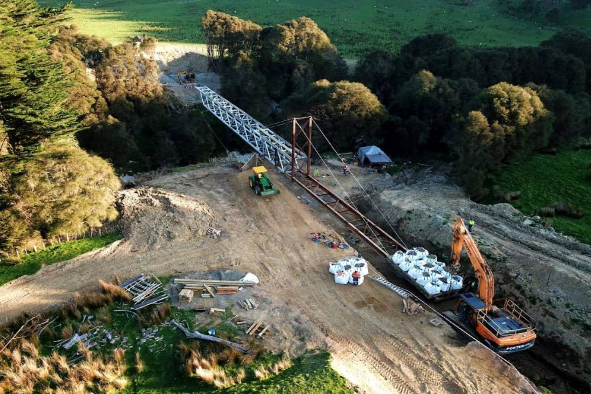 Aerial photo of bridge construction over a forested area with cranes and machinery
