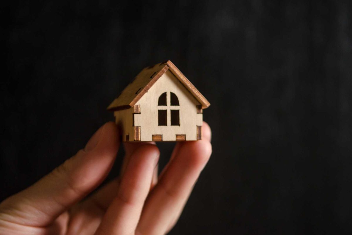 Hand holding a small wooden house model