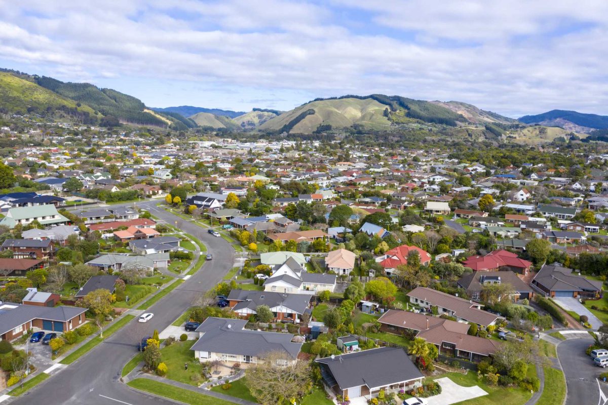 Aerial view of a suburban neighborhood with houses and green hills in the background