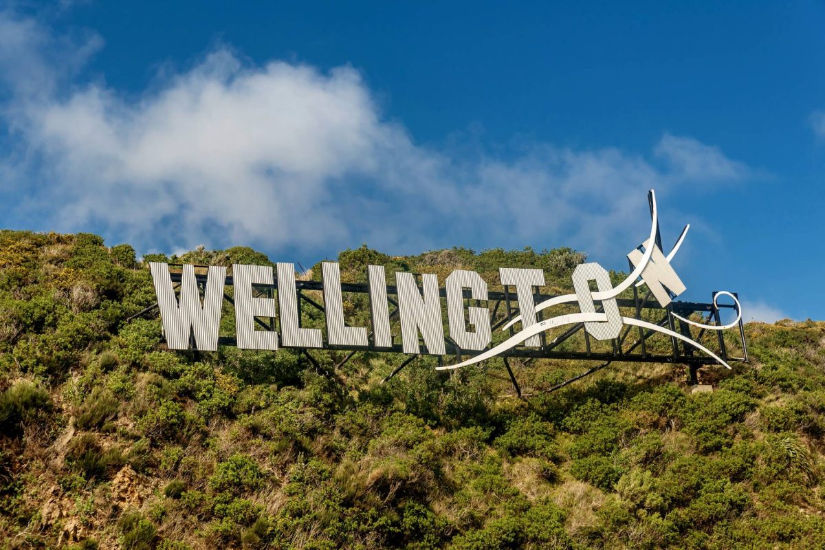 Large “Wellington” hillside sign with stylized wind design against a blue sky