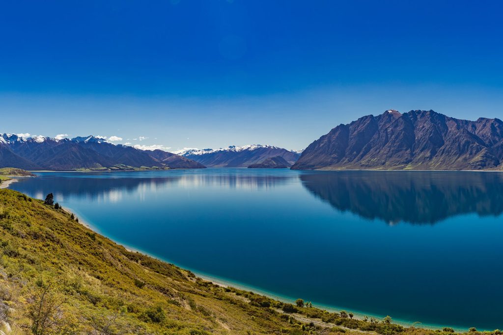 Panoramic views of Lake Hawea surrounded by rugged mountains and open New Zealand landscape