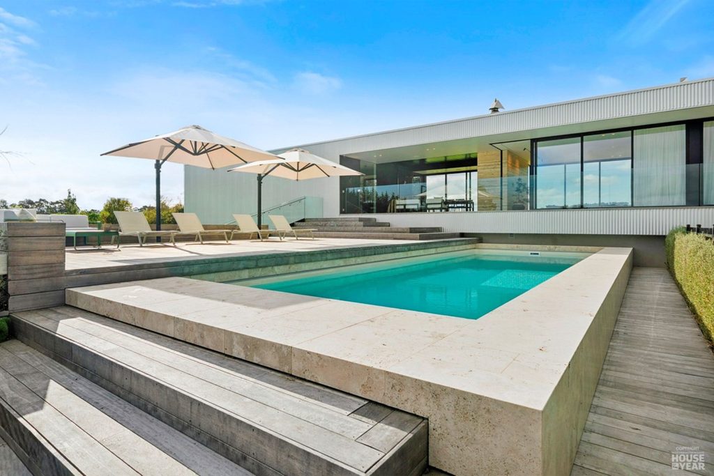 Planit Construction's Martinborough home with a swimming pool, landscaped outdoor living area and modern white exterior.