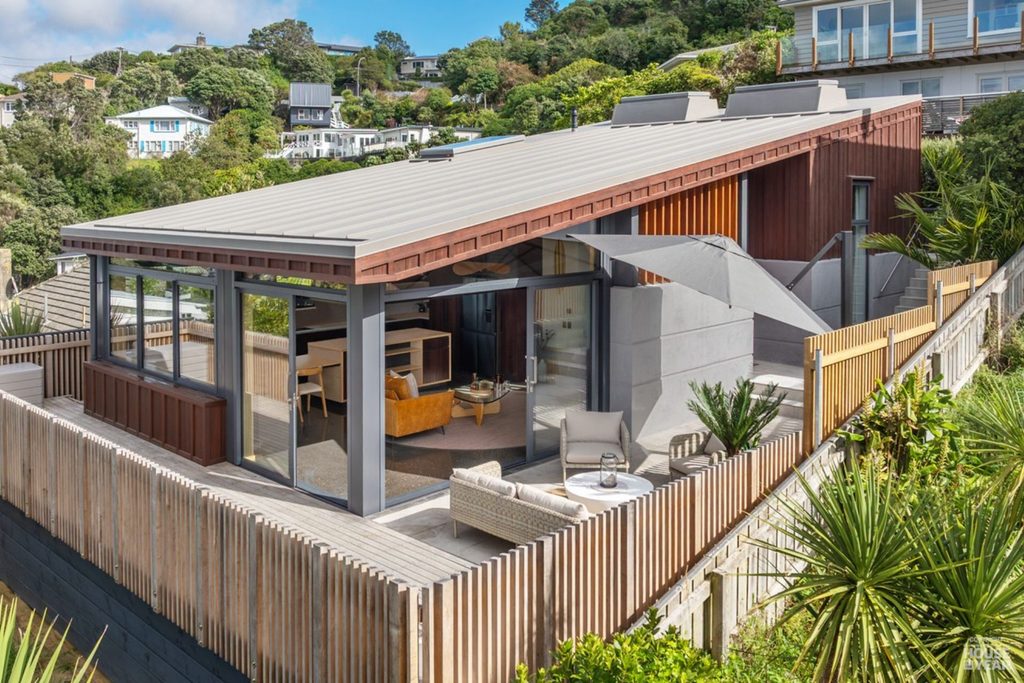 Class E Build's Roseneath home built on a steep hillside site, with timber cladding, a sloping roof and outdoor deck.